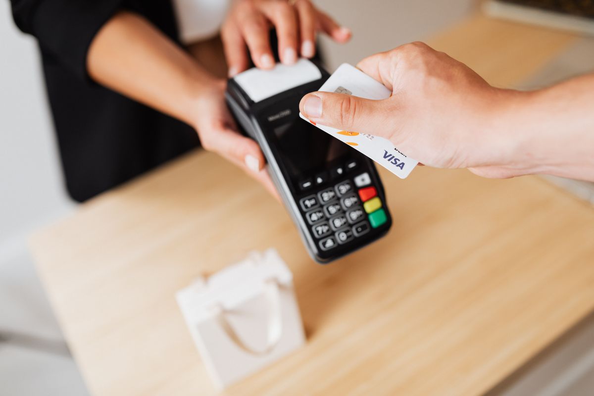 Hand tapping a credit card on a payment terminal