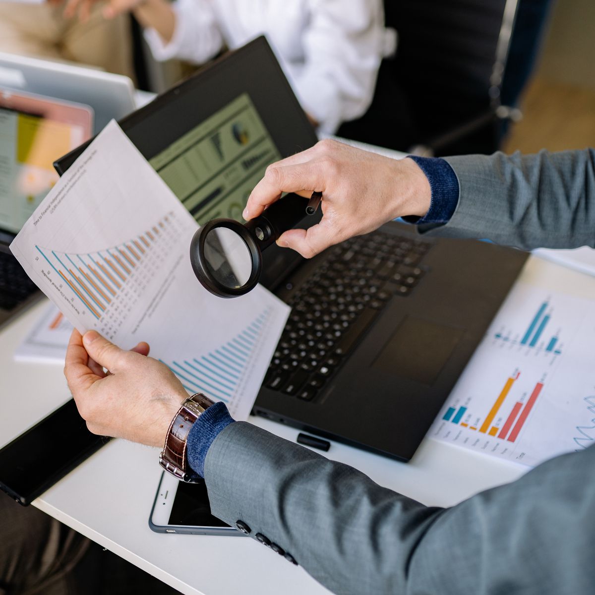 Businessman examining financial charts with a magnifying glass