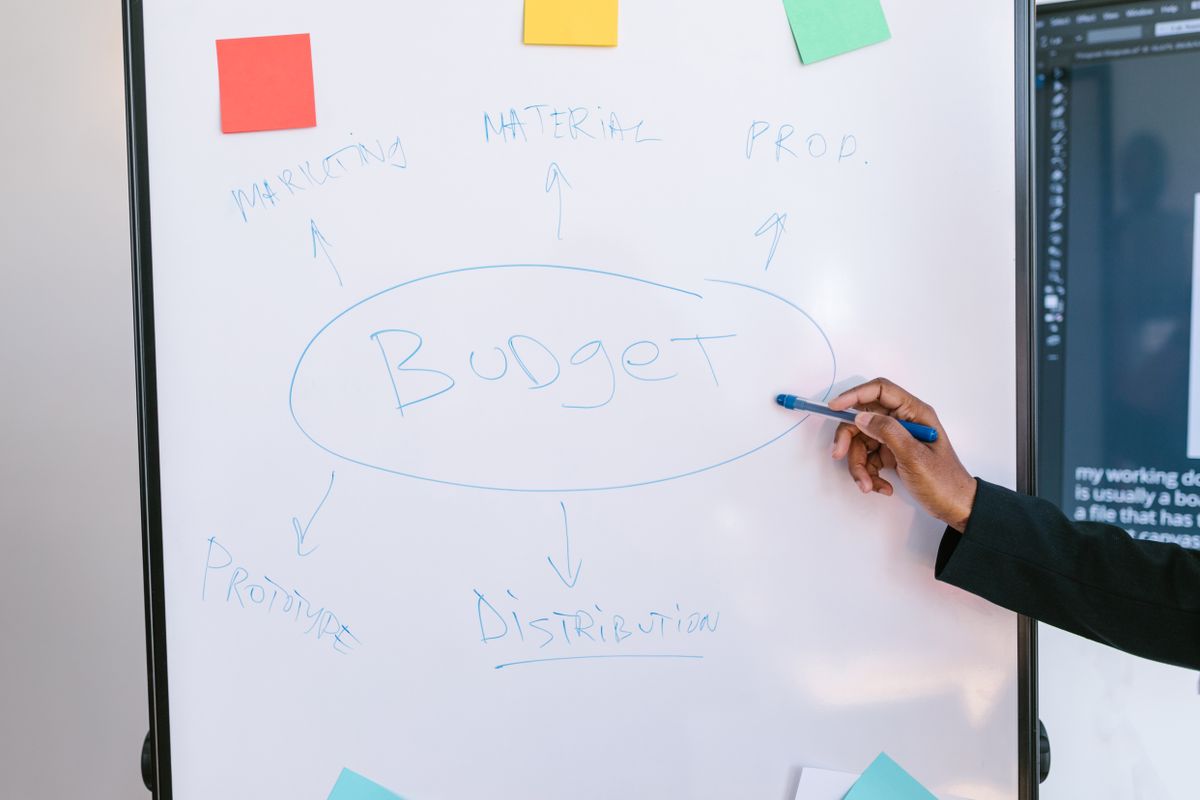 Hand mapping out a budget plan on a whiteboard