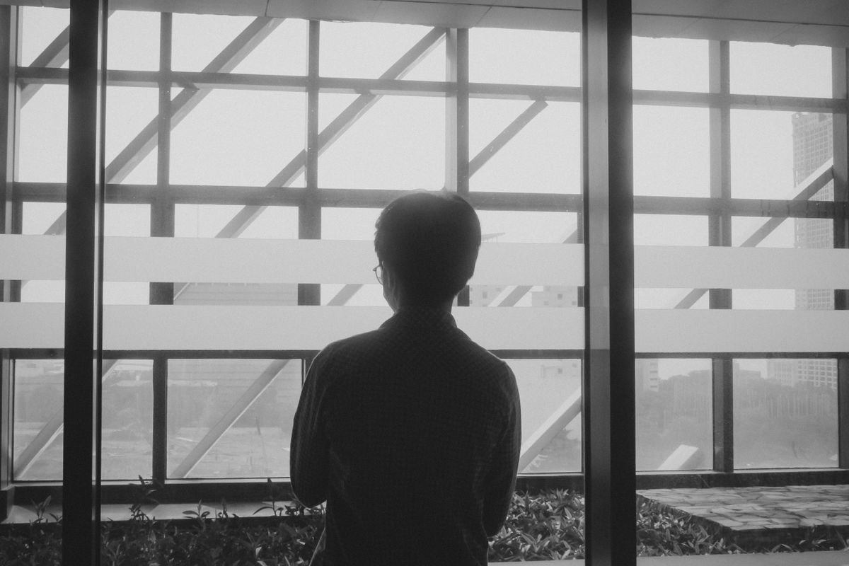 Silhouette of a person looking out over a city skyline through a large window